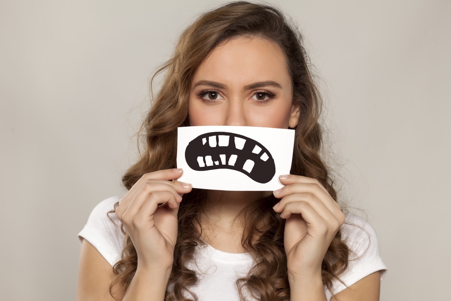 Woman covering smile with broken and mishapen teeth