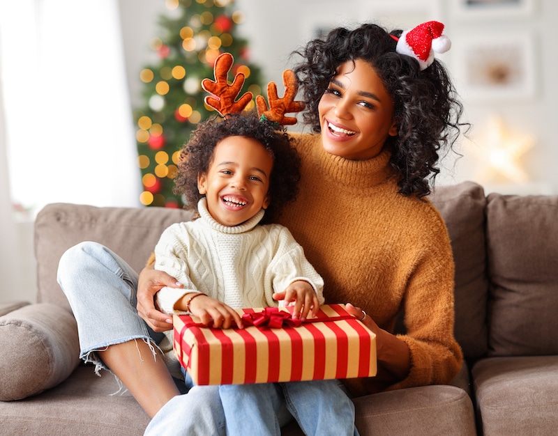 Mom and child smiling in front of Christmas tree