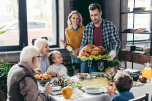 man with delicious turkey for holiday dinner with beautiful family 300x200 1