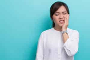 asian woman holding her cheek because of toothache