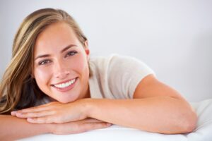 A woman smiling and showing the results of a full mouth reconstruction procedure