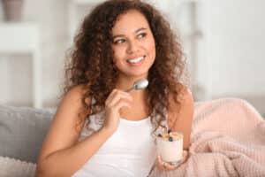 Woman eating soft foods while recovery from dental implant surgery at home in Boulder