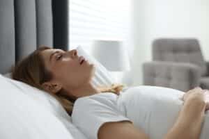 Woman laying down sleeping with mouth open due to sleep apnea in Boulder, CO