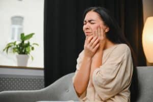 Woman holding her jaw in pain from TMJ disorder symptoms in Boulder, CO