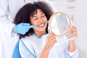 Woman smiling in dentist chair after root canal in Boulder, CO